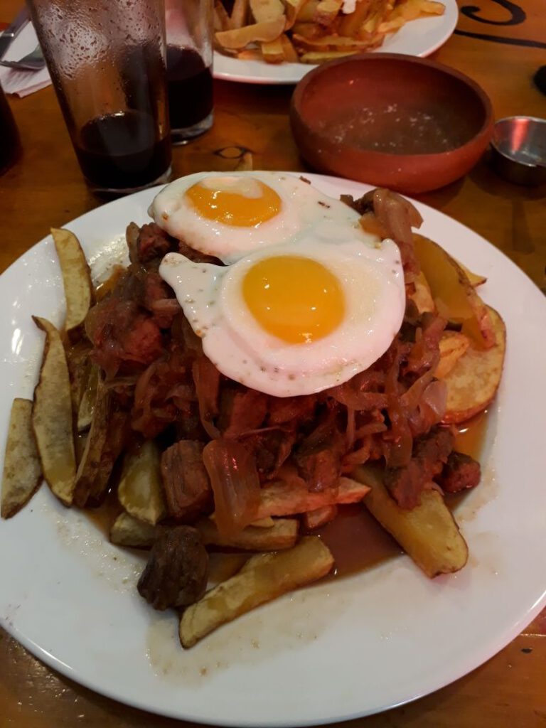 Traditional Chilean fish with fries, onions and fried eggs